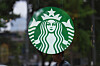 Starbucks-logo på et skilt i Seoul med uskarp bybakgrunn.