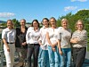 Sju kvinner står side om side på en terrasse med natur og himmel bak.
