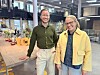 Smilende mann og kvinne står side ved side i et moderne kontorlandskap.