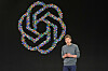 Sam Altman står på en scene foran OpenAI-logoen under en konferanse i San Francisco.
