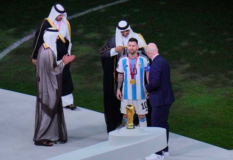 Kappekledd VM-vinner: Emiren i Qatar, sjeikTamim bin Hamad Al Thani, overrasket mange med å legge en tradisjonell kappe kalt «bisht» rundt skuldrene på Lionel Messi før han løftet pokalen etter Argentinas seier mot Frankrike i finalen. Da tok det fyr i vestlige medier. Foto; NTB.