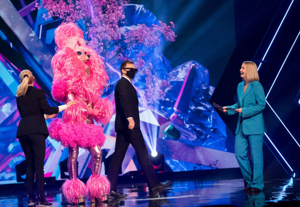 Gjettelek: Hvem som skjuler seg i puddel-kostymet får ikke TV-seerne svar på før kjendisen ryker ut av konkurransen. I mellomtiden skal det gjettes. Programleder Silje Nordnes til høyre. Foto: NRK