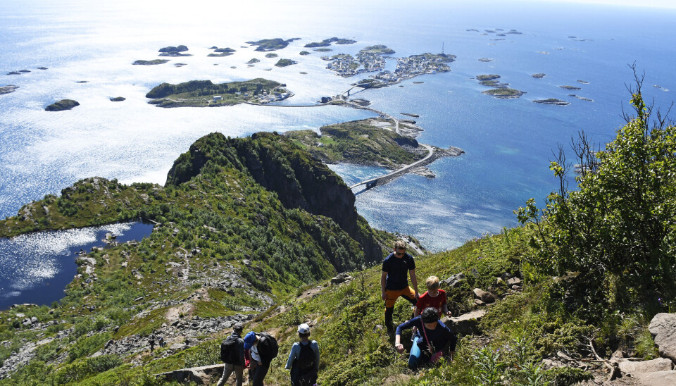 Turister på toppen av Festvågtinden ved Henningsvær, i Lofoten. Hvert år strømmer turistene til stedene i Lofoten.