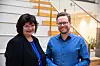 Cathrine Hagen og Jan Berthrand Danielsen står og smiler foran en innendørs trapp i et kontorbygg